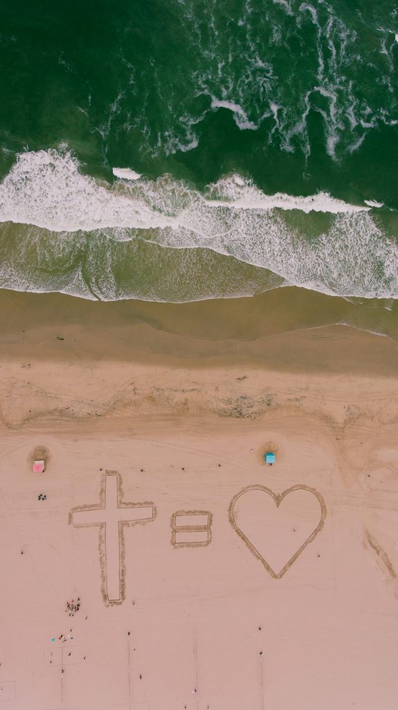 cross is love - sand with beach and waves from above